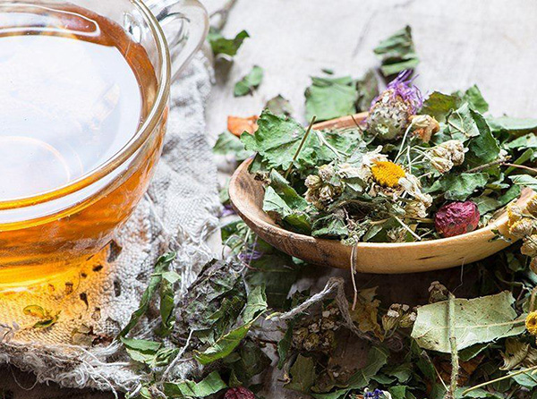 Glass teapot with herbal infusion and teaware on a tray